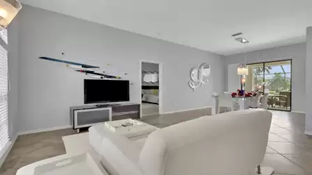 Open living and dining area with TV, wall art, white sofa and patio doors