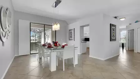 Glass dining table with white chairs, red dishes and sliding doors to lanai