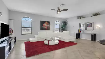 Living room with white sectional sofa, red rug, TV stand and glass coffee table