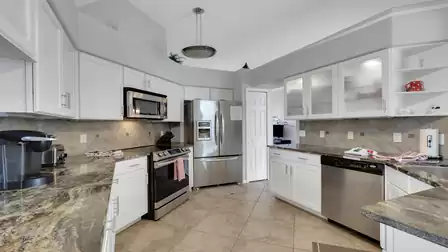U shaped kitchen with white cabinets, granite counters, stainless appliances and tiled floor