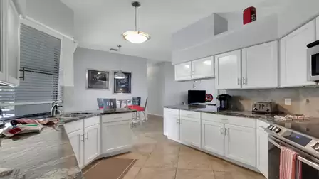White kitchen with granite counters, stainless appliances and small dining nook with TV