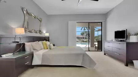 Bedroom with dark wood furniture, wall mirror and sliding door to pool area