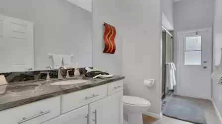 Bathroom with granite vanity, toilet, walk in shower and door with frosted window
