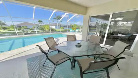 The dining area on the patio offers a serene view of pool and canal