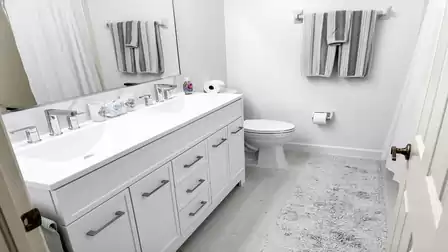 All-white bathroom with double sink, bathtub with shower and WC