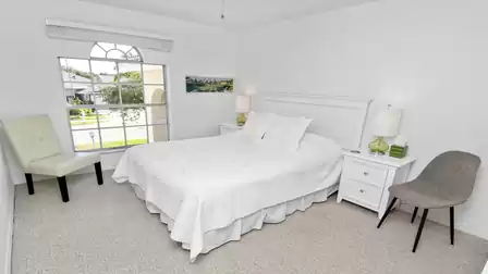 Chic bedroom all in white with queen size bed and view of the garden