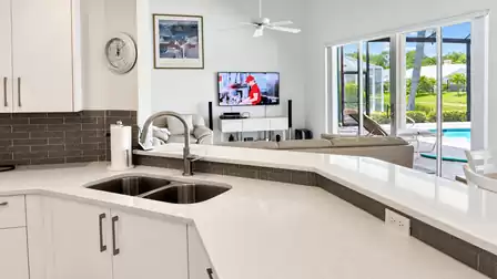 Modern open-plan kitchen and living area with views of the pool and waterfront.