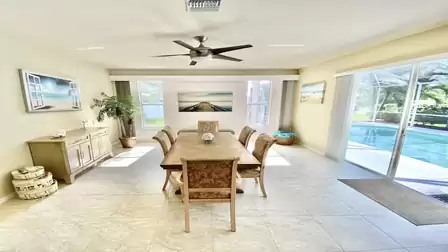 Floor-to-ceiling sliding glass doors provide a view of the pool from the dining area