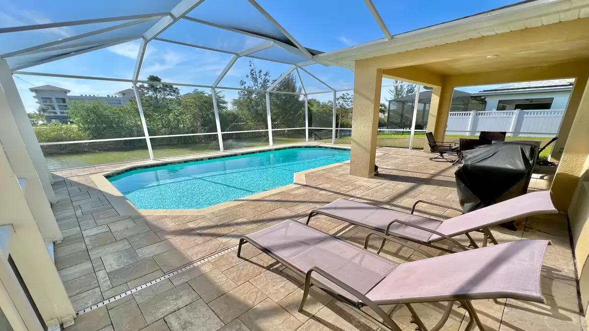Pool deck with sun loungers and covered dining area.
