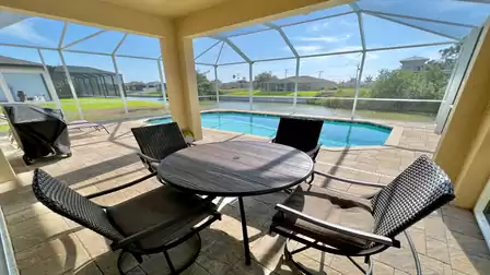 Covered patio with dining table and canal view.