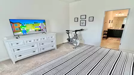 Bedroom with TV and exercise bike.