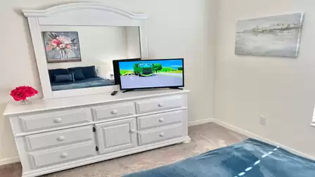 Comfortable sleeping area with a TV, dresser, and charming decorations.