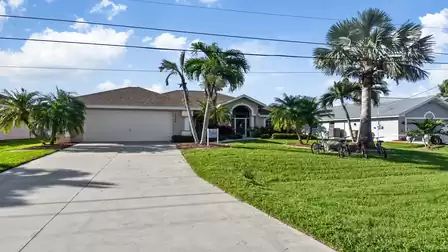 A large lawn and palm trees decorate the entrance of the villa