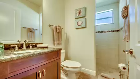 Elegant bathroom with dark wood vanity, granite countertop, modern shower with glass wall, and stylish seashell decorations.