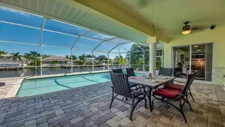 Covered terrace with dining area overlooking the pool and canal.