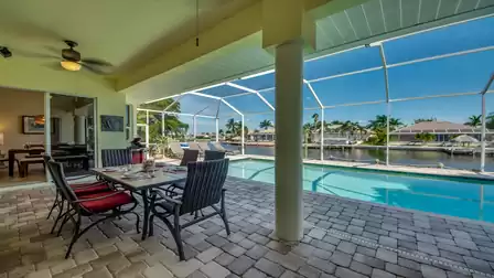 Outdoor dining area with pool view under a covered terrace.