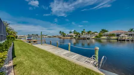 Private boat dock of Villa Donatella with direct access to the canal, surrounded by well-maintained lawn and tropical vegetation.