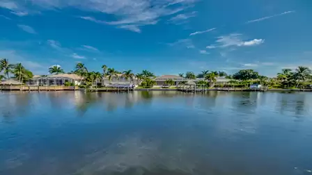 Expansive view over the canal with luxurious villas and lush palm scenery along the shore.