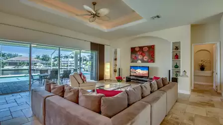 Spacious living area with a cozy sofa landscape, modern decor, and direct view of the pool area.