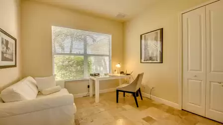 Bright home office with desk, comfortable seating, and a large window overlooking the greenery.