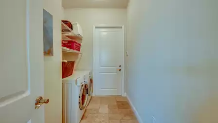 Functional laundry room with a washing machine, dryer, and storage space for laundry and cleaning supplies.