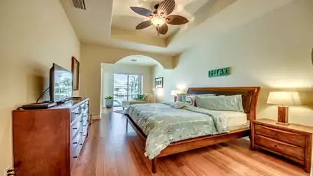 Spacious master bedroom with a king-size bed, stylish furniture, and direct access to the terrace with a pool view.