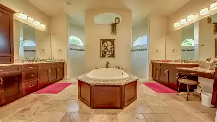 Luxurious bathroom with a central bathtub, two vanity areas, and modern lighting.