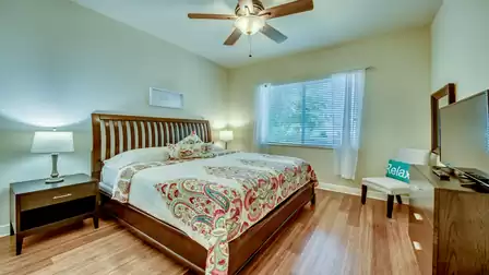 Cozy guest bedroom with a wooden bed, ceiling fan, and stylish decor.