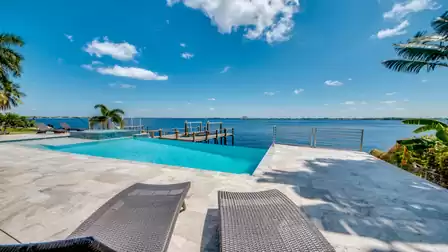 Dreamy pool area with river views and tropical palm trees.
