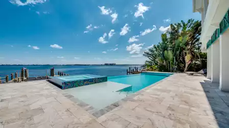 Spacious pool deck with lounge furniture and covered outdoor area.