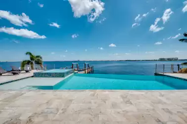Infinity pool with an integrated hot tub and river view.
