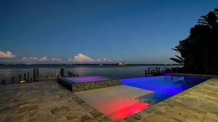 Illuminated pool area with colorful lighting effects and night panorama.