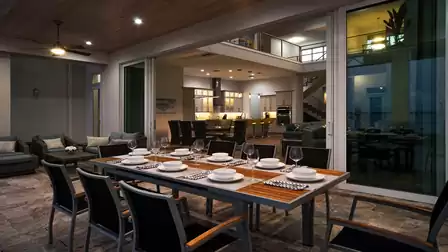 Elegantly set dining table on the covered terrace with a view into the stylish living area of Villa River King.