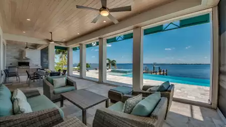 Luxurious covered terrace with comfortable lounge furniture, ceiling fans, and a breathtaking river view.