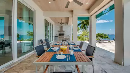 Large dining table on the terrace set for a relaxed meal overlooking the water.