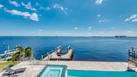 Infinity pool with hot tub and direct view of the river and boat dock.
