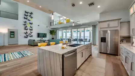 Open kitchen with marble island, living area, and access to terrace with waterfront view.