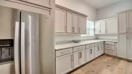 Butler’s pantry with ample storage, marble countertops, and large refrigerator.