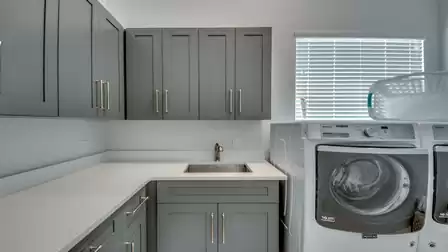 Modern laundry room with washer, dryer, and gray built-in cabinets.