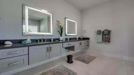 Spacious bathroom with double sinks, modern LED-lit mirrors, and stylish gray cabinets.
