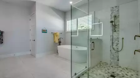 Luxurious bathroom with a freestanding bathtub, large glass shower, and elegant wall design in soft tones.