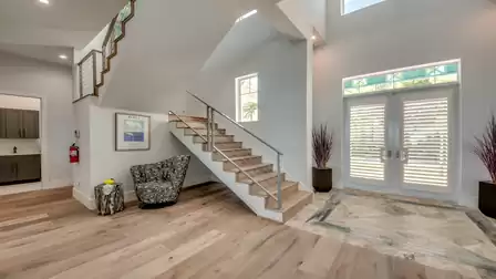 Open entrance area with a stylish wooden staircase and metal railing, elegant decor, and modern design.