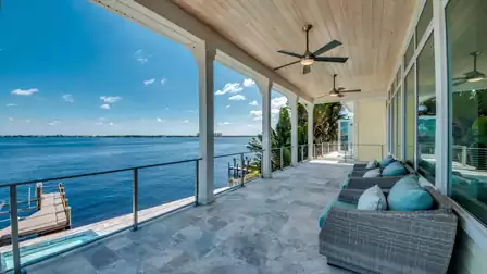Covered terrace with cozy lounge furniture, ceiling fans, and a stunning river view.