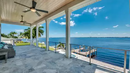 Spacious terrace with seating area, glass railing, and a view of the dock and water.