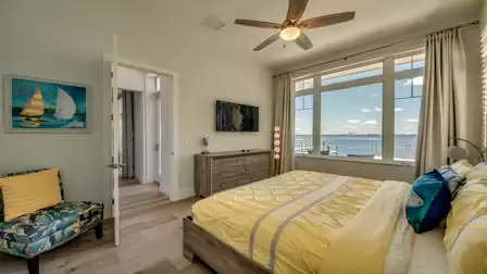 Elegant bedroom with yellow bedding, large windows, and direct view of the river.