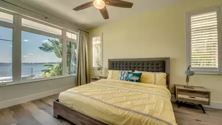 Bright bedroom with yellow bedding, large window, and water view.