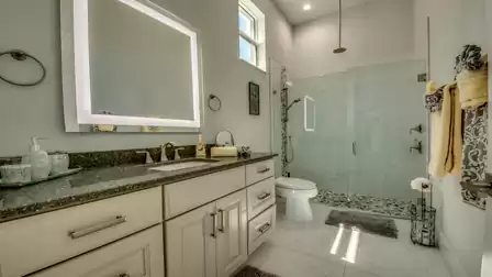 Modern bathroom with large illuminated mirror, glass shower, and stylish details.