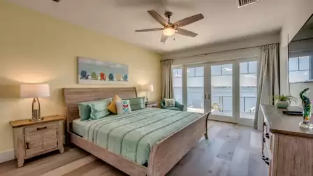 Cozy bedroom with green bed, wooden frame, and direct access to the balcony with water view.