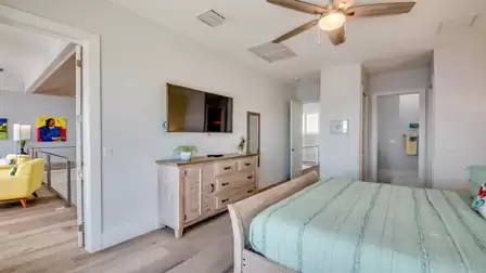 Bedroom with rustic dresser, wall TV, and view of the modern gallery.