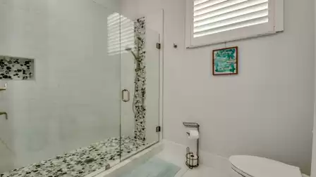 Spacious shower with glass wall, mosaic tiles, and elegant fixtures.